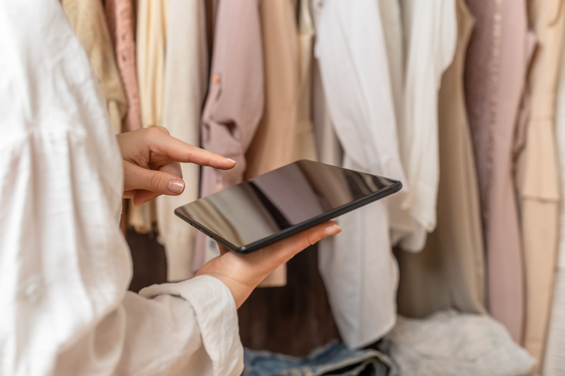 Female entrepreneur holding tablet while doing inventory in her trendy clothing shop
